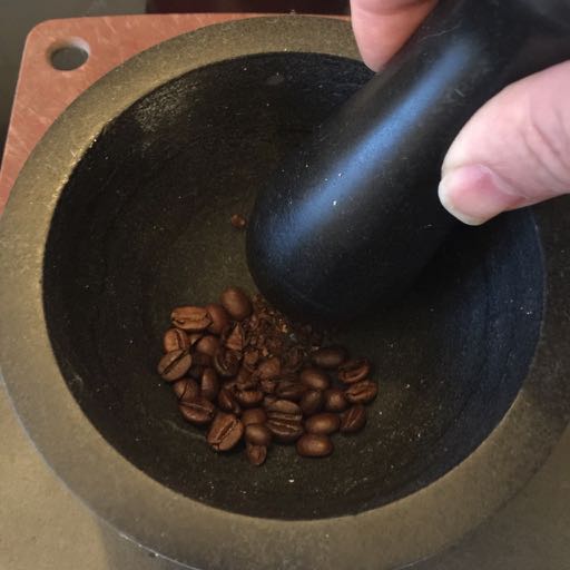 Mortar and Pestle grinding roasted coffee.
