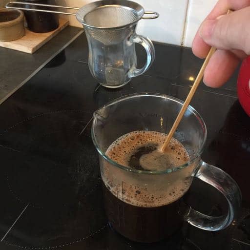 Stirring the brewing coffee with a chopstick.
