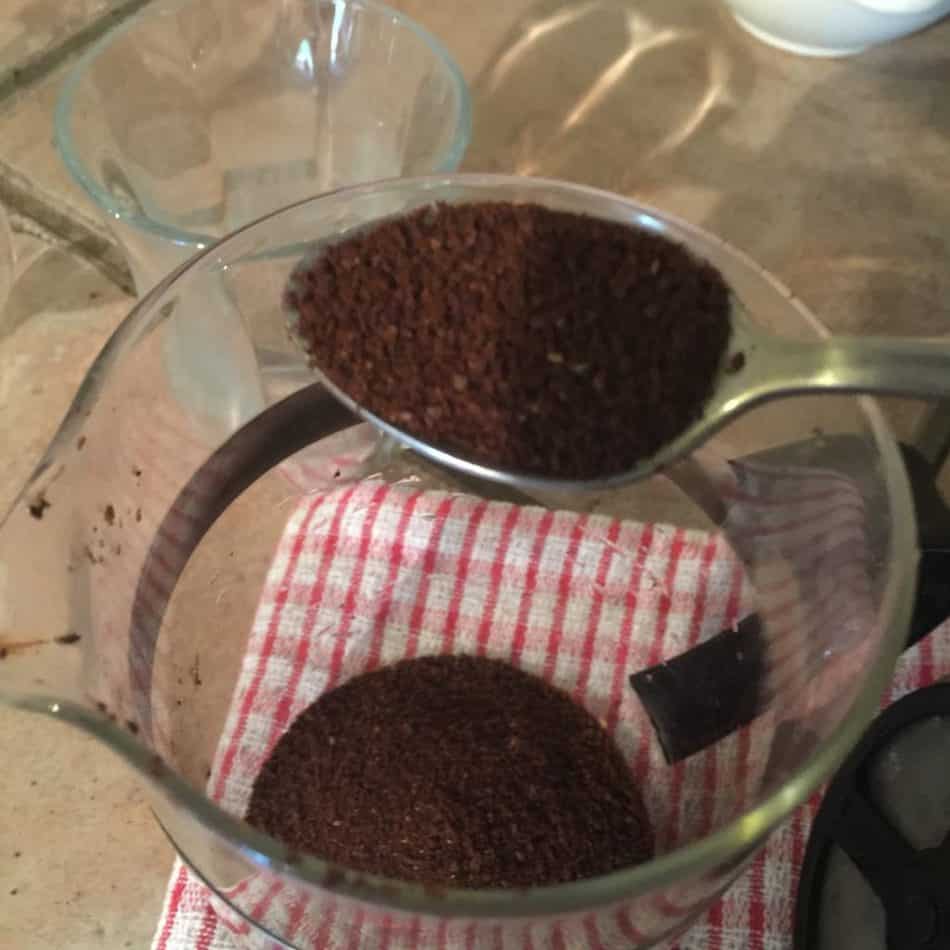 One final teaspoon of ground coffee being put into a french press